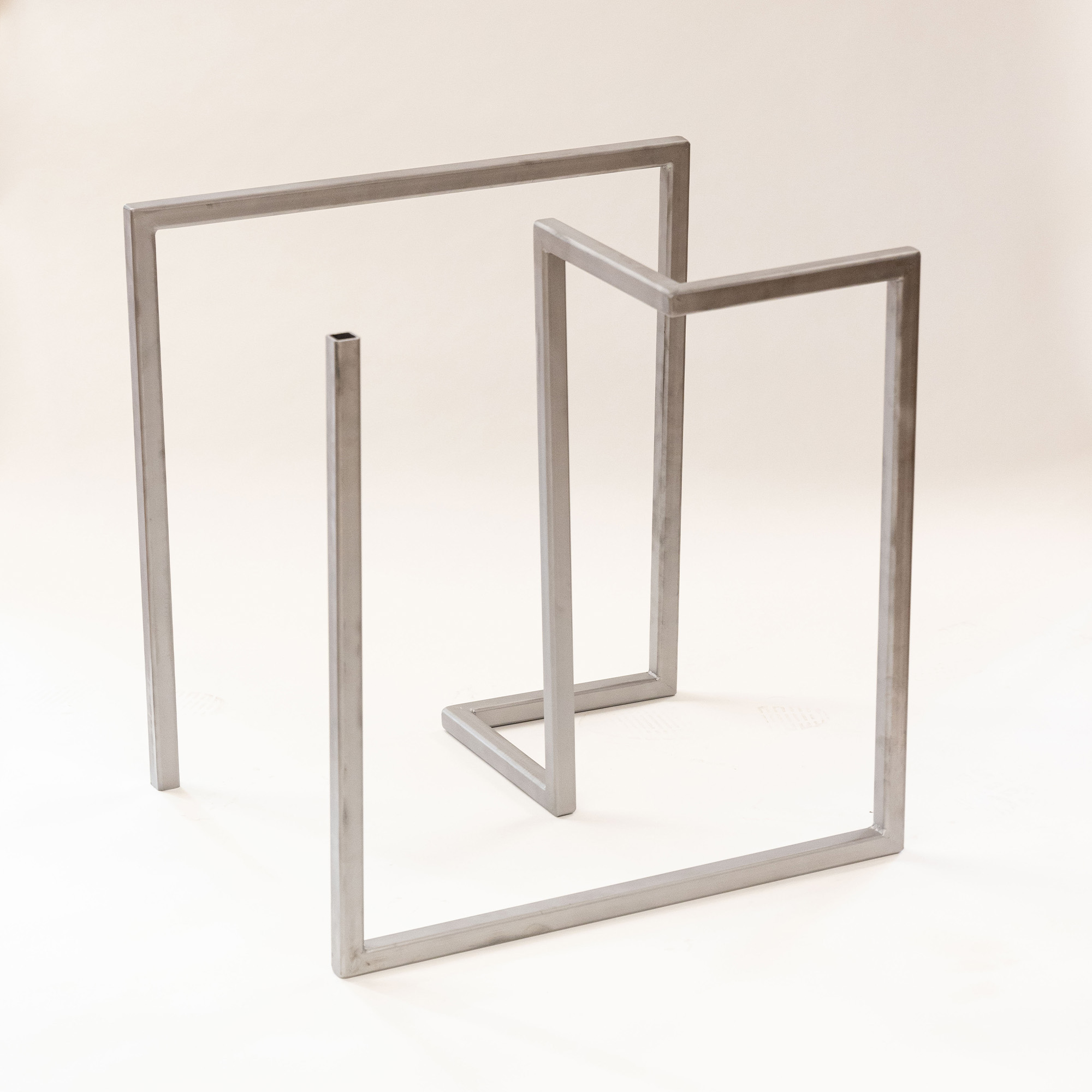 Minimalist metal table frame with a geometric rectangular design on a light background.