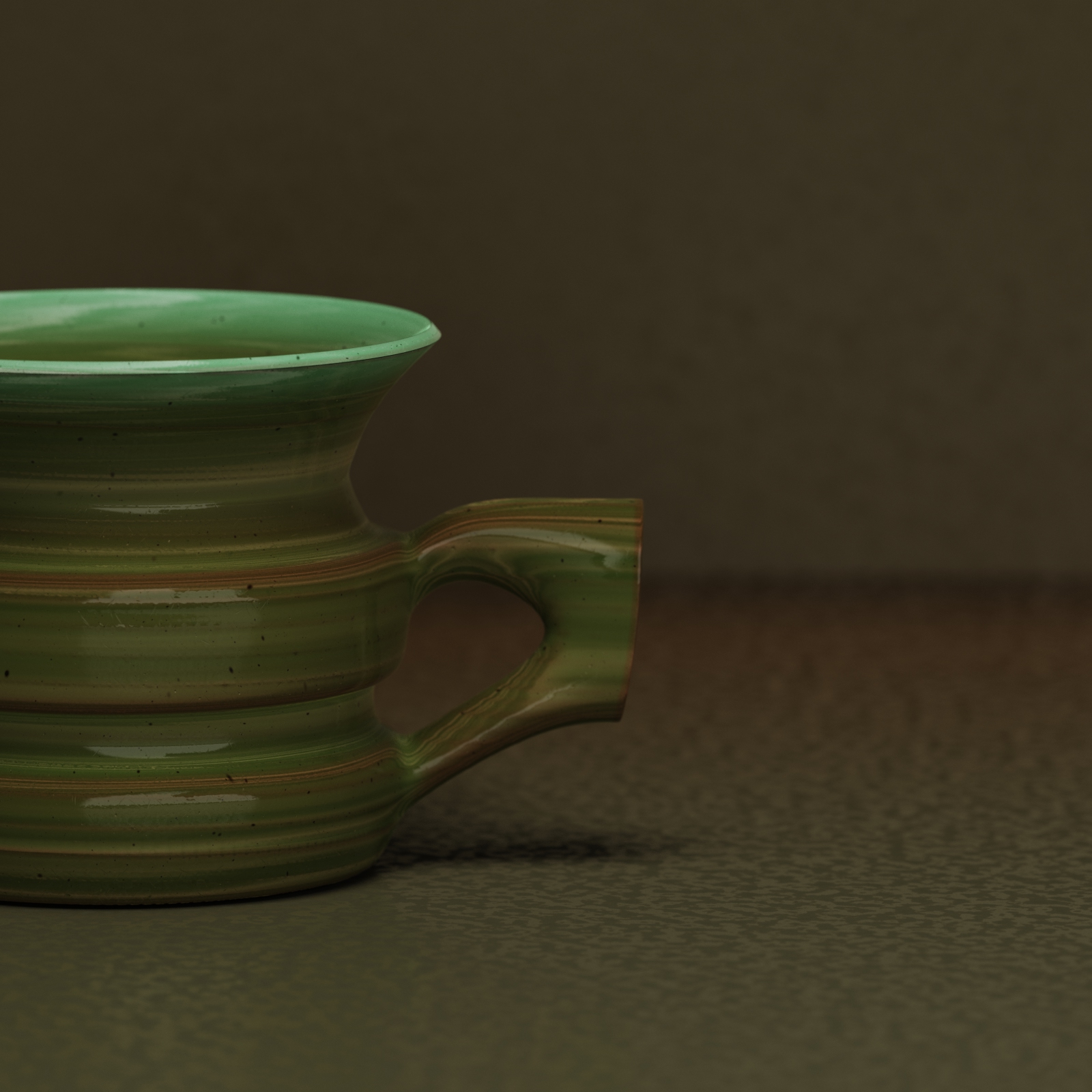 Close-up of a green ceramic cup with horizontal stripes and a handle, placed on a textured surface.