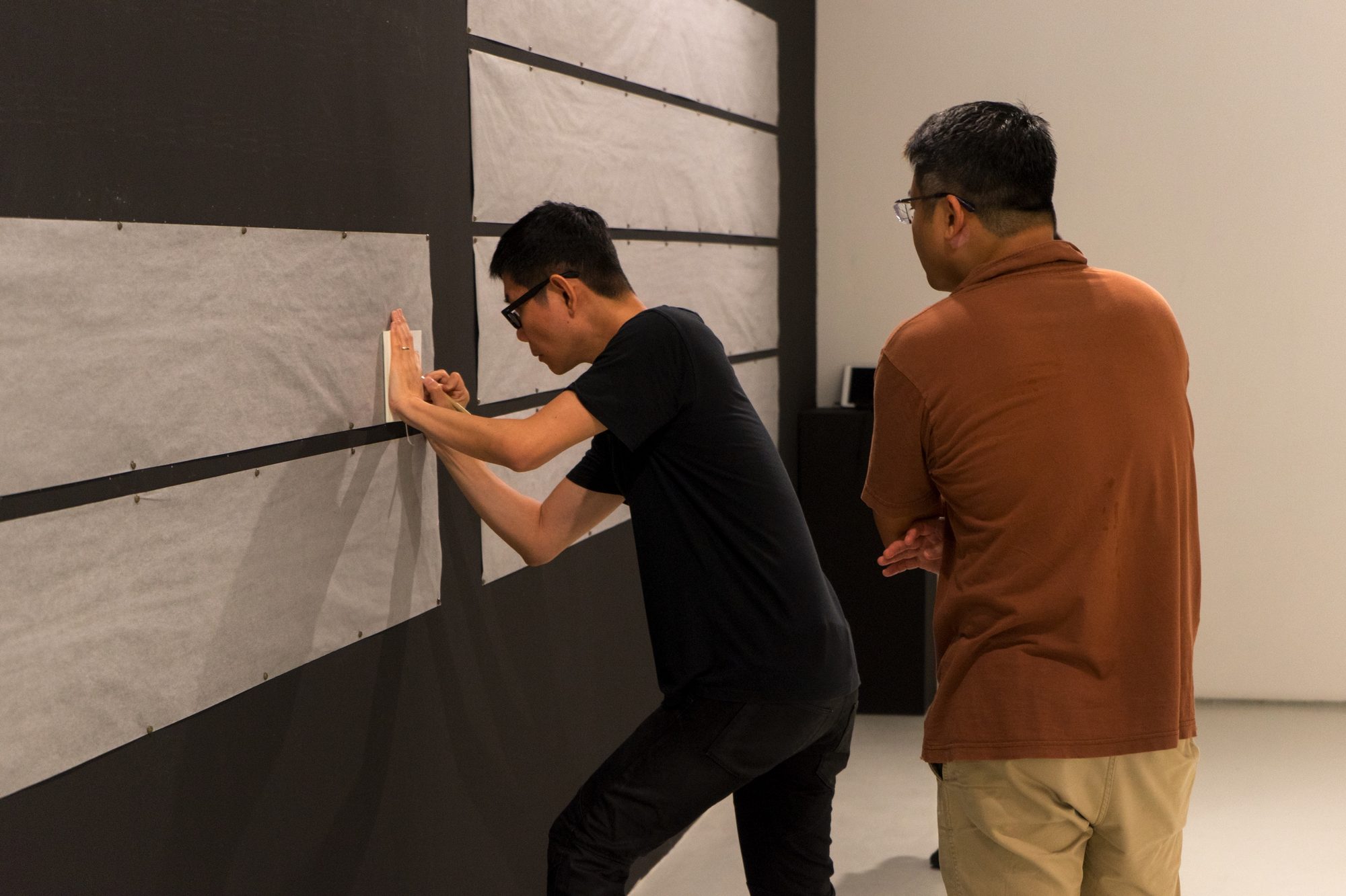 Boedi pressing lines onto the wall while a visitor watches