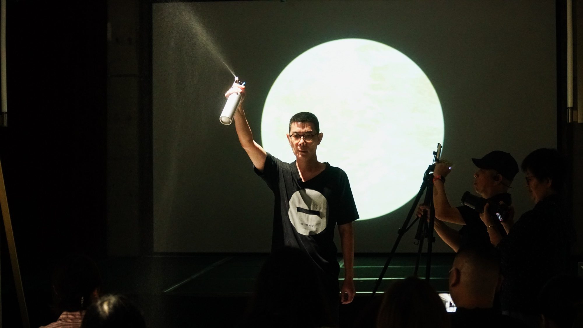 Boedi spraying mist into the air in front of a projected circle