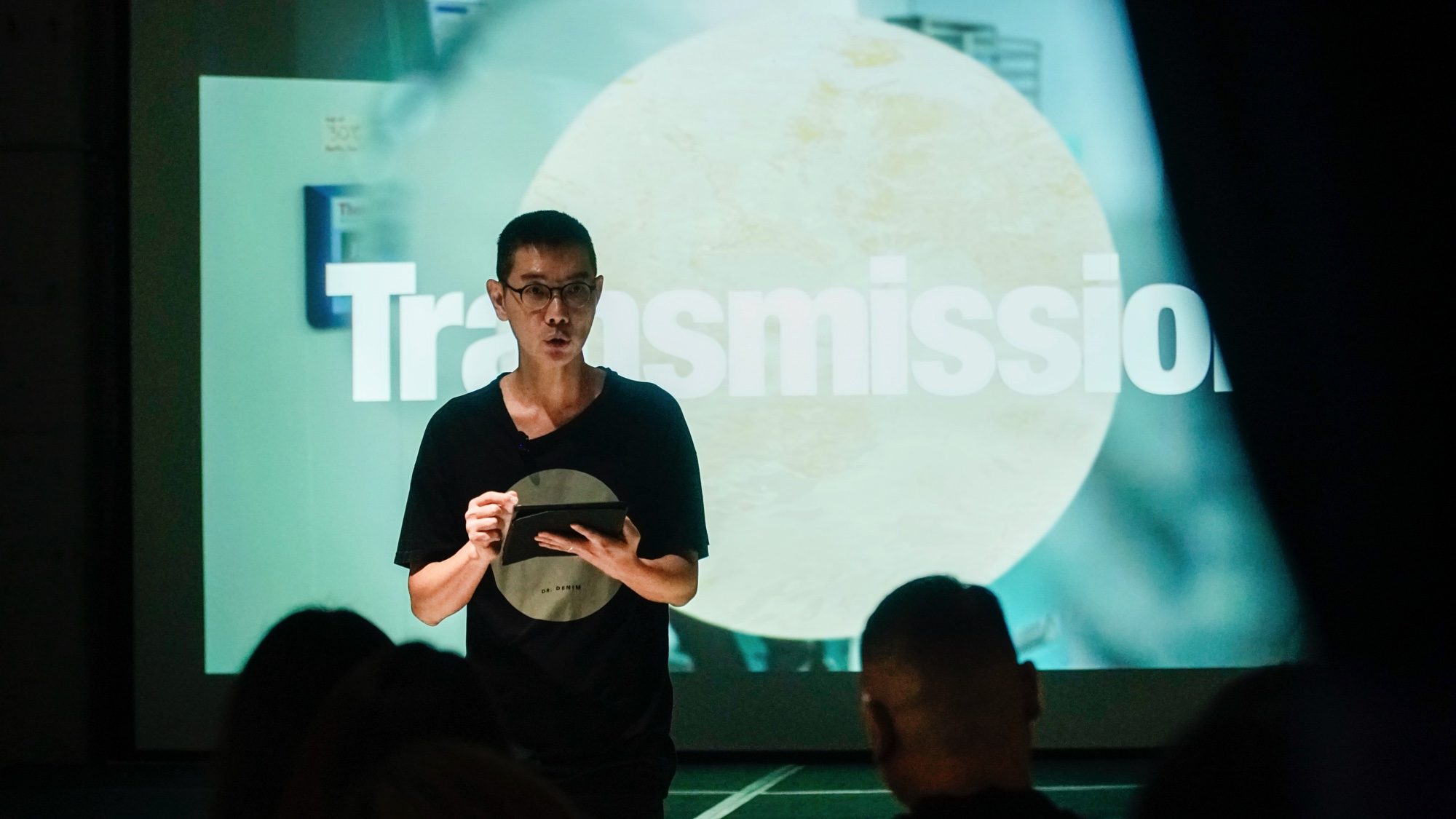 Boedi speaking before a projection reading Transmission