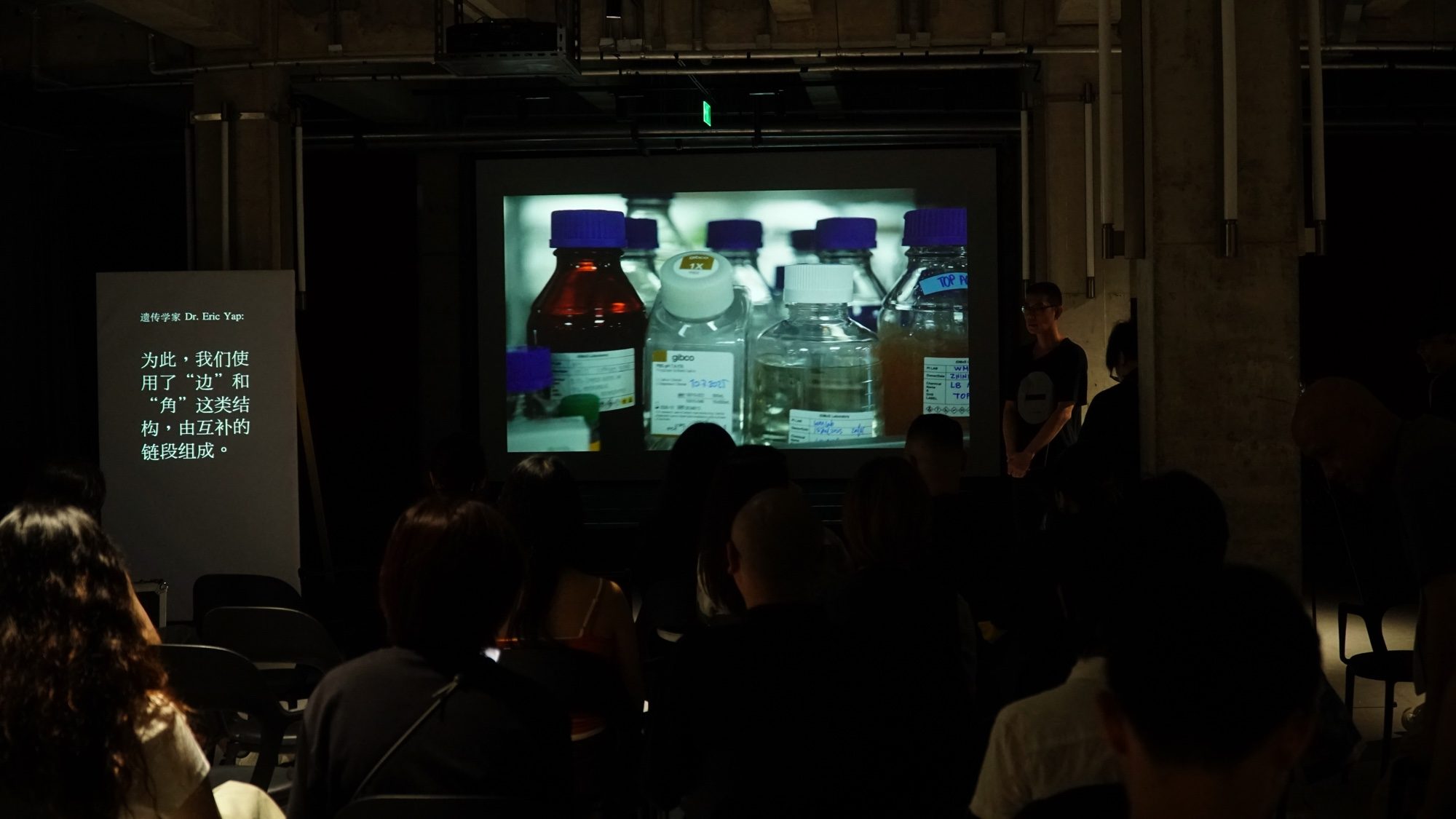 Audience watching a projection of laboratory bottles