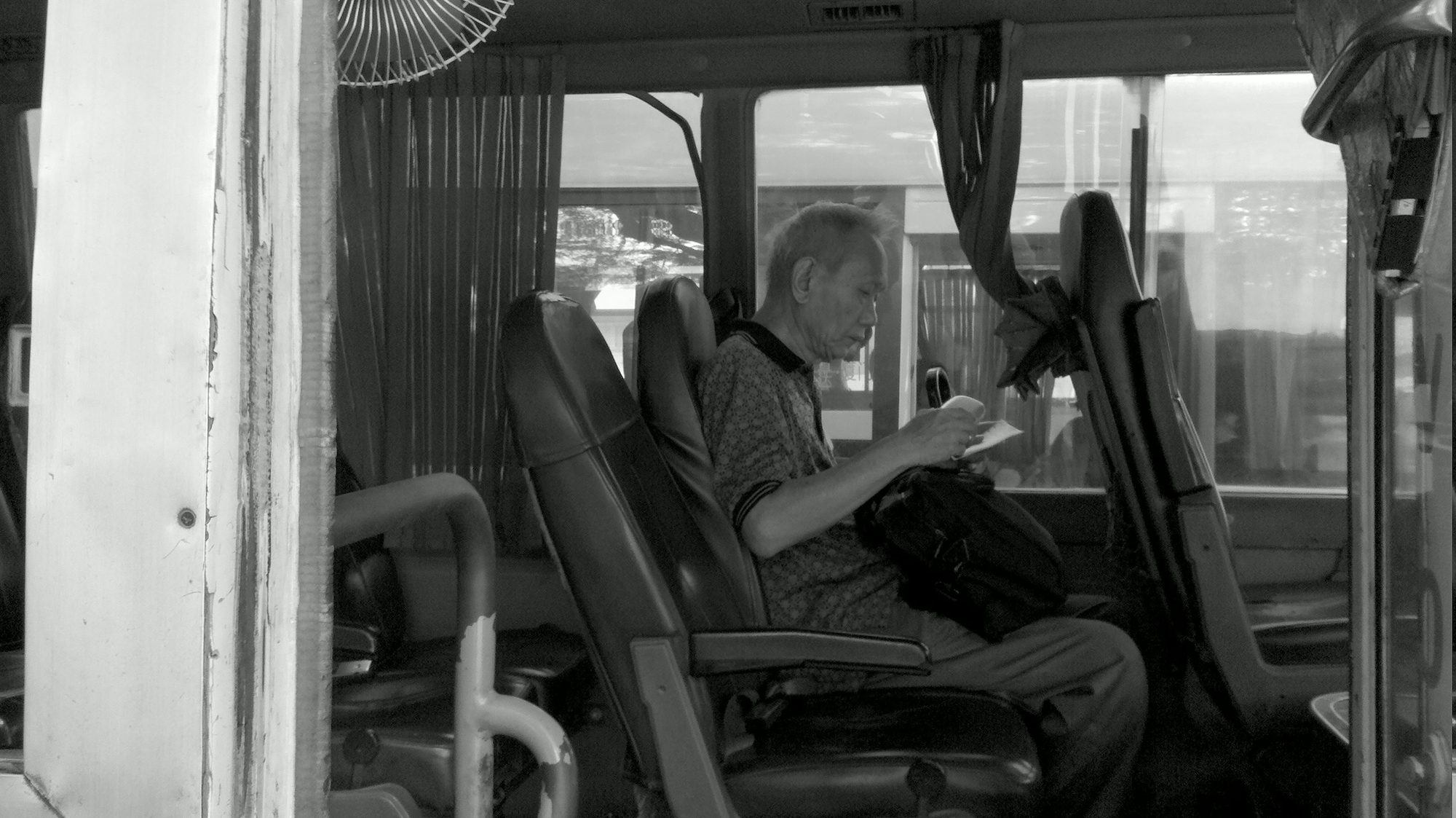 An older man reading on a bus