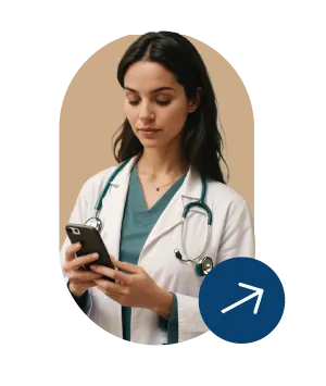 Female doctor in white coat with stethoscope looking at smartphone against a light brown background.