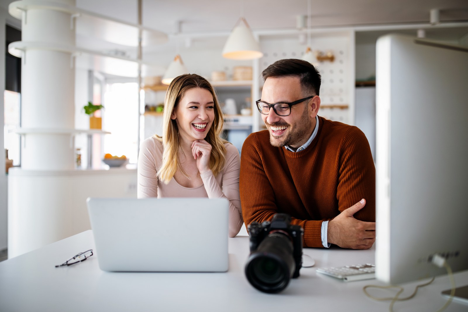 A couple smiling while viewing a laptop.