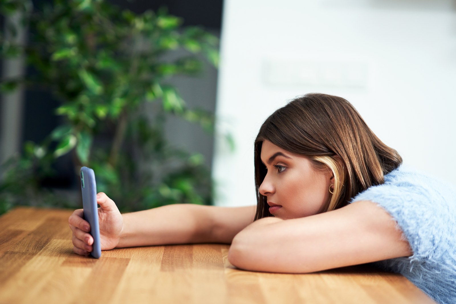 A uninterested woman scrolling through her feed on her phone.