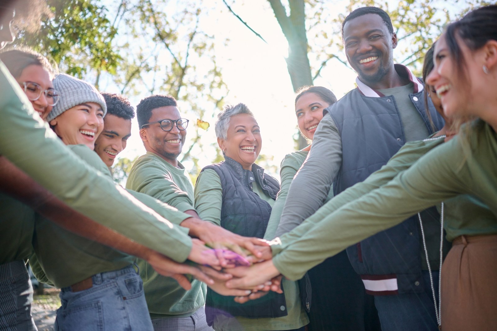A group of people being putting their hands together as a community.