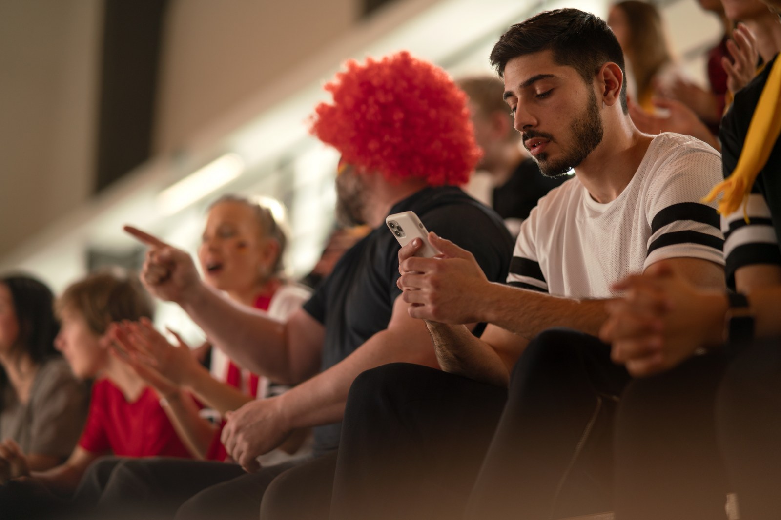 A sports fan looking at his mobile phone during a game.