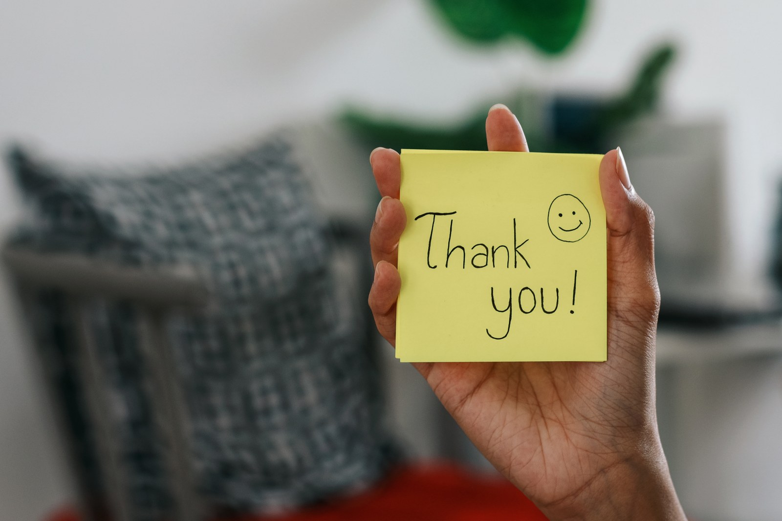 A person holding a post note saying “Thank you!”