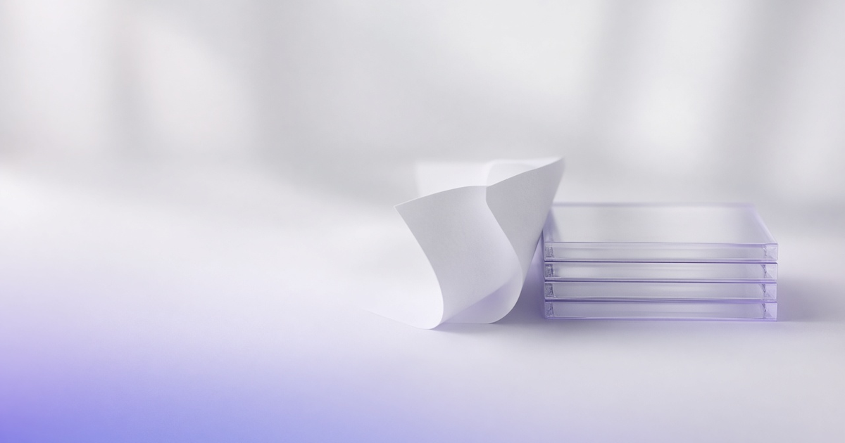 Curled paper sheet beside an aligned stack of clear glass cards, representing structured partner data