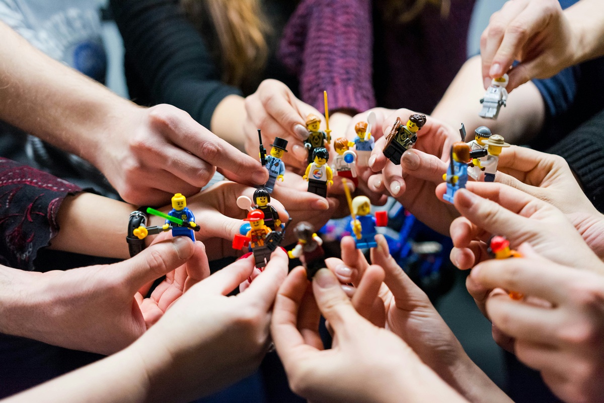 Viele Hände halten LEgo-Figuren in den Fingern und berühren sich.