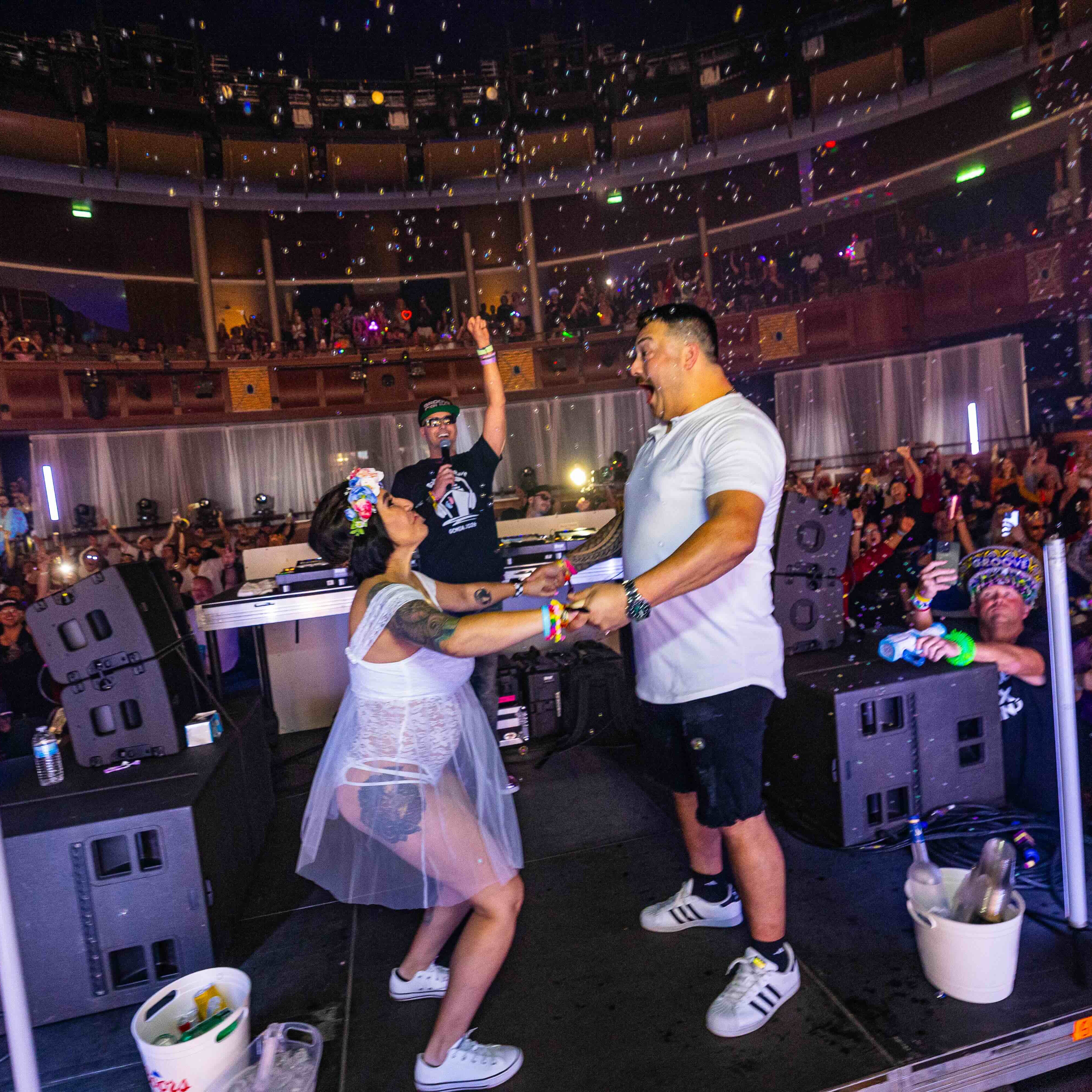 A couple holds hands onstage as confetti falls and the Groove Cruise crowd cheers around them.