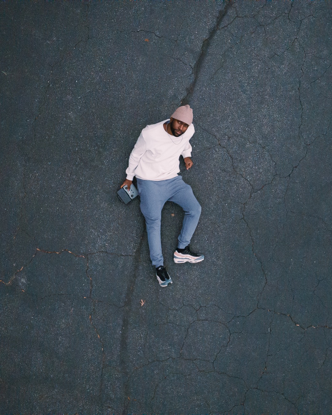 fashionable futurist neutrals wearing black man 90 degrees birds eye drone shot on asphalt
photo by Chrishaun Byrom