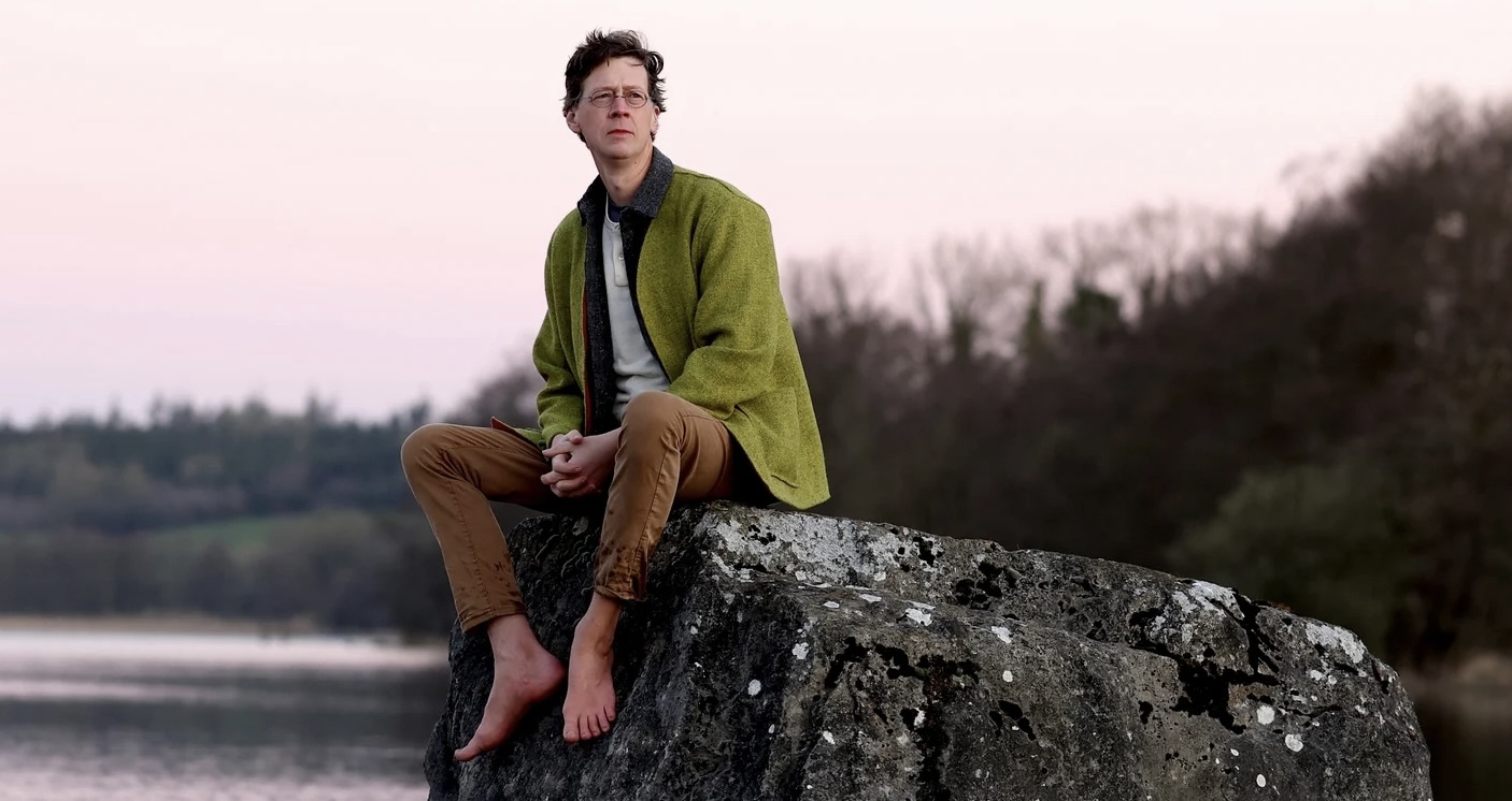 Person sitting on a rock by the water staring