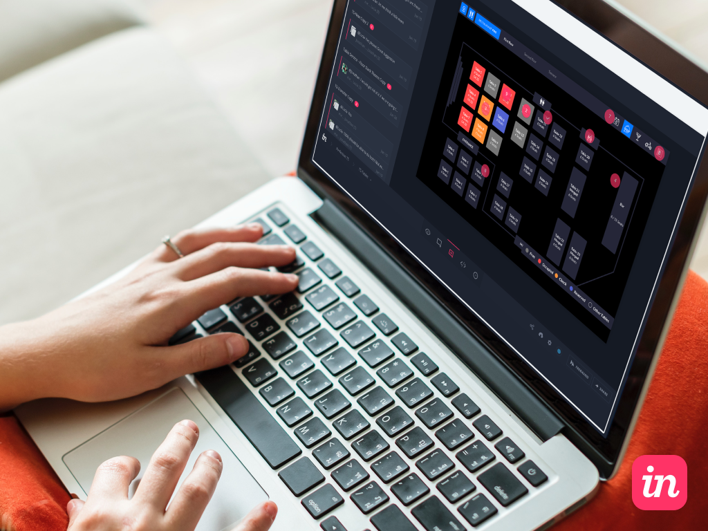 Person using a laptop with a hand on the keyboard and another near the trackpad, viewing a software interface that appears to be a site map or wireframe layout with various labeled blocks and sections in a dark-themed design.