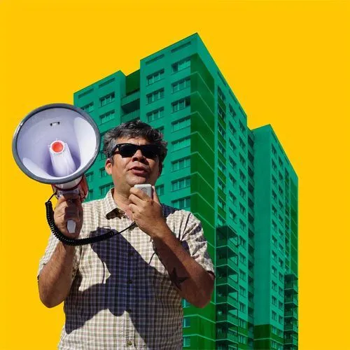 person speaks into bullhorn in front of yellow sky and green building