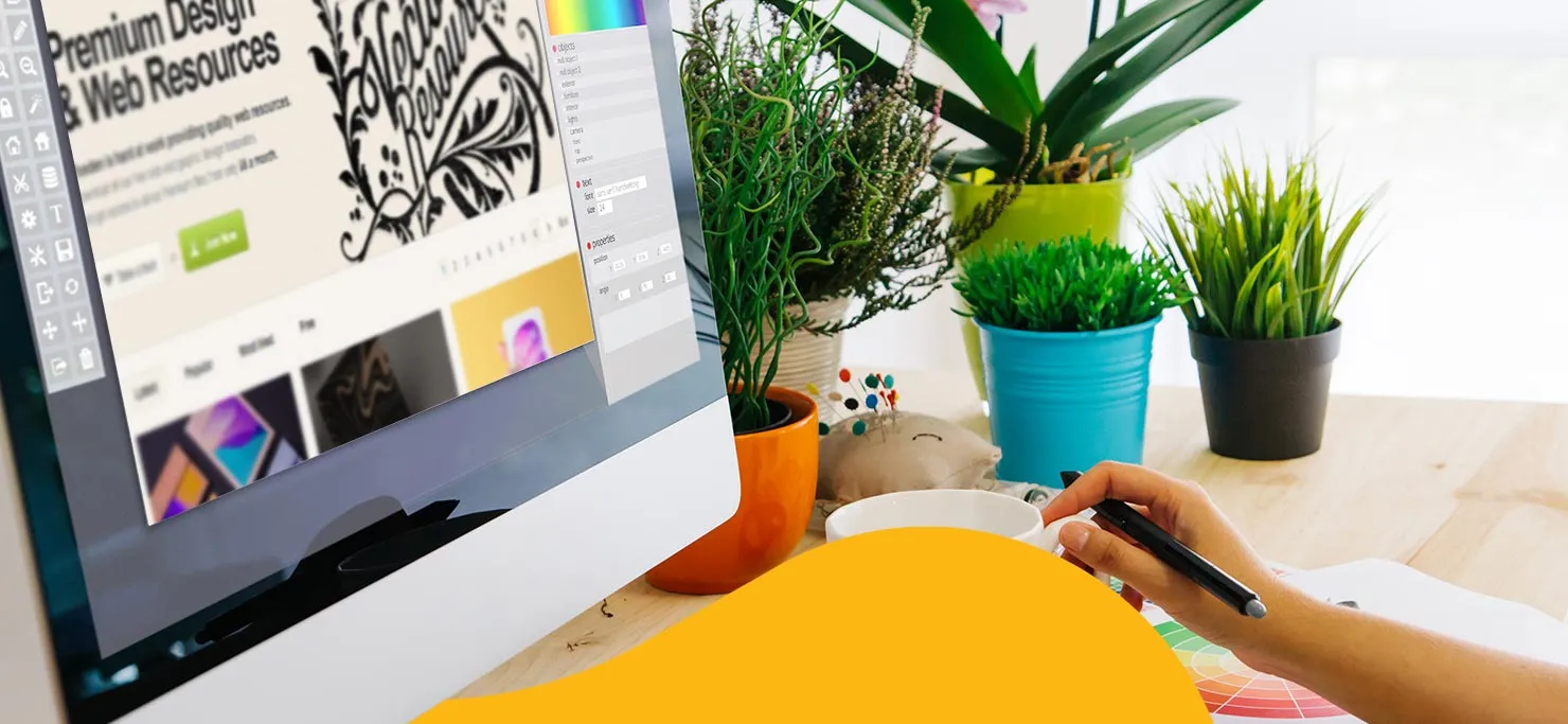 A designer looks through graphic design resources on the internet. The workspace is surrounded by houseplants.