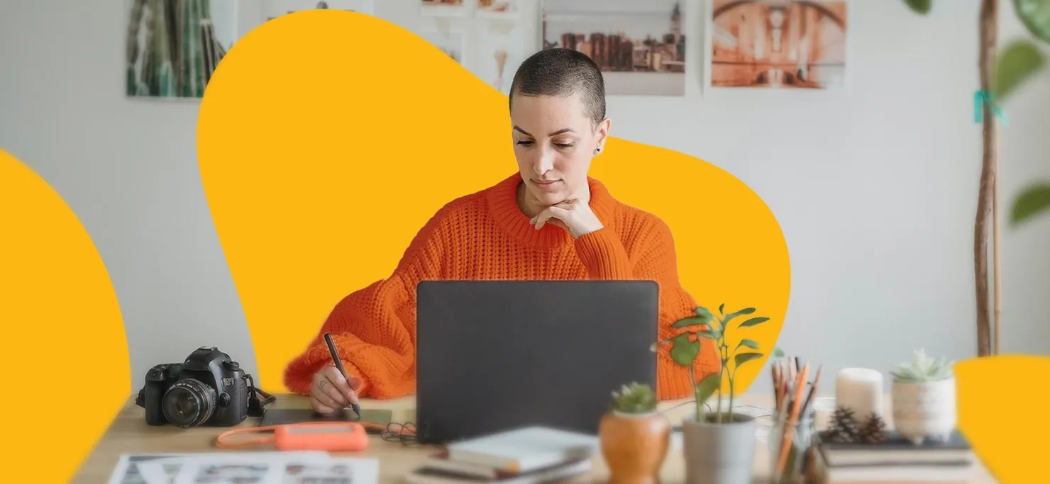 A woman works on her laptop. There is a camera at her side.