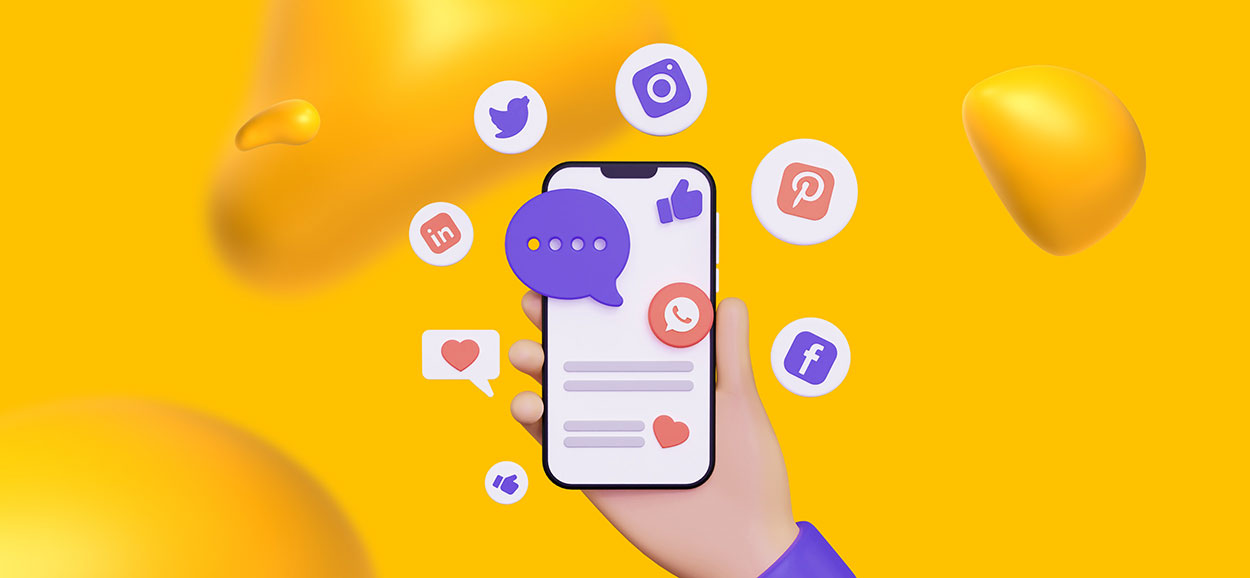 A hand holding a smartphone. On the screen are various logos for different social media platforms.