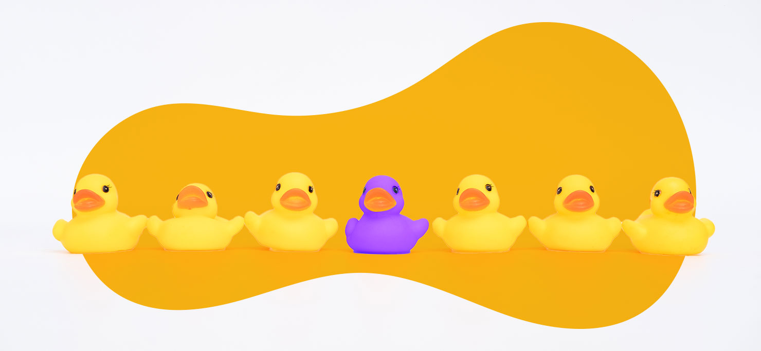 six yellow ducks with one purple duck in the middle.