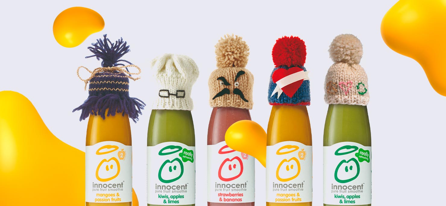 Five smoothie bottles with labels that differ by flavor and color. They all have different colored beanies on their top.