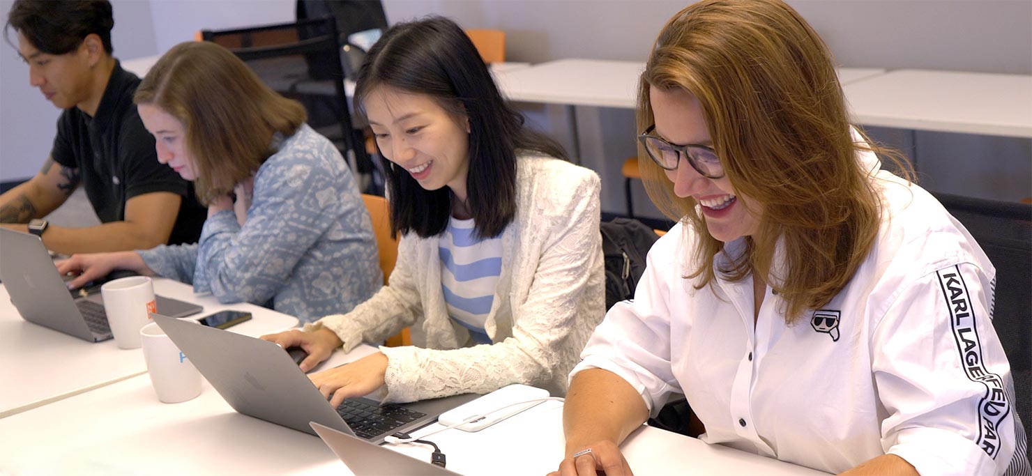 A group of Designity employees cheerfully work on their laptops.
