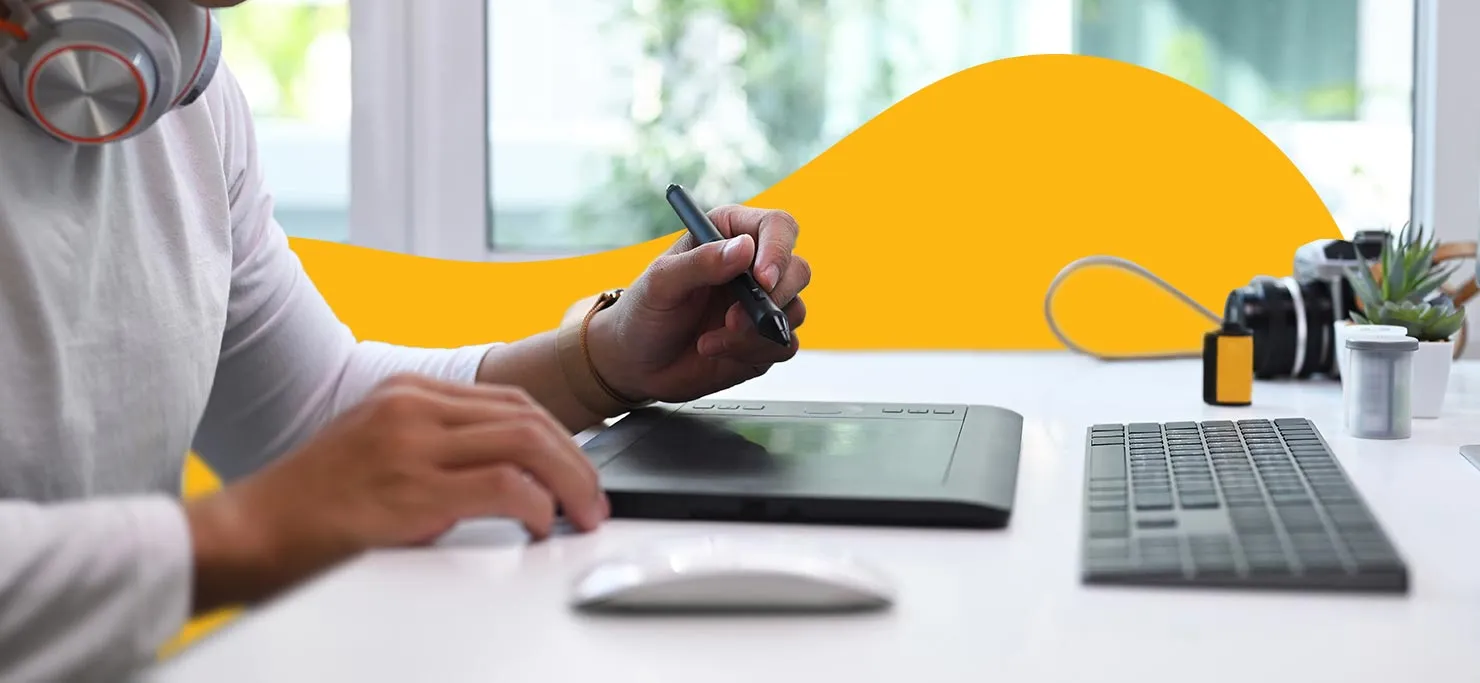 A graphic designer using a drawing tablet with stylus.