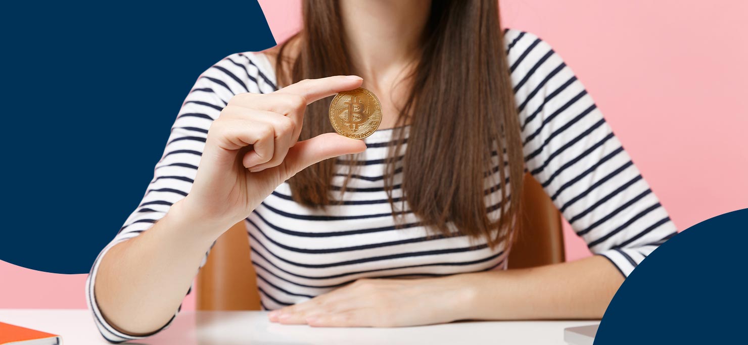 A woman in a black and white striped shirt. She is holding up a gold coin for the camera. Set against a navy and pink Designity background.