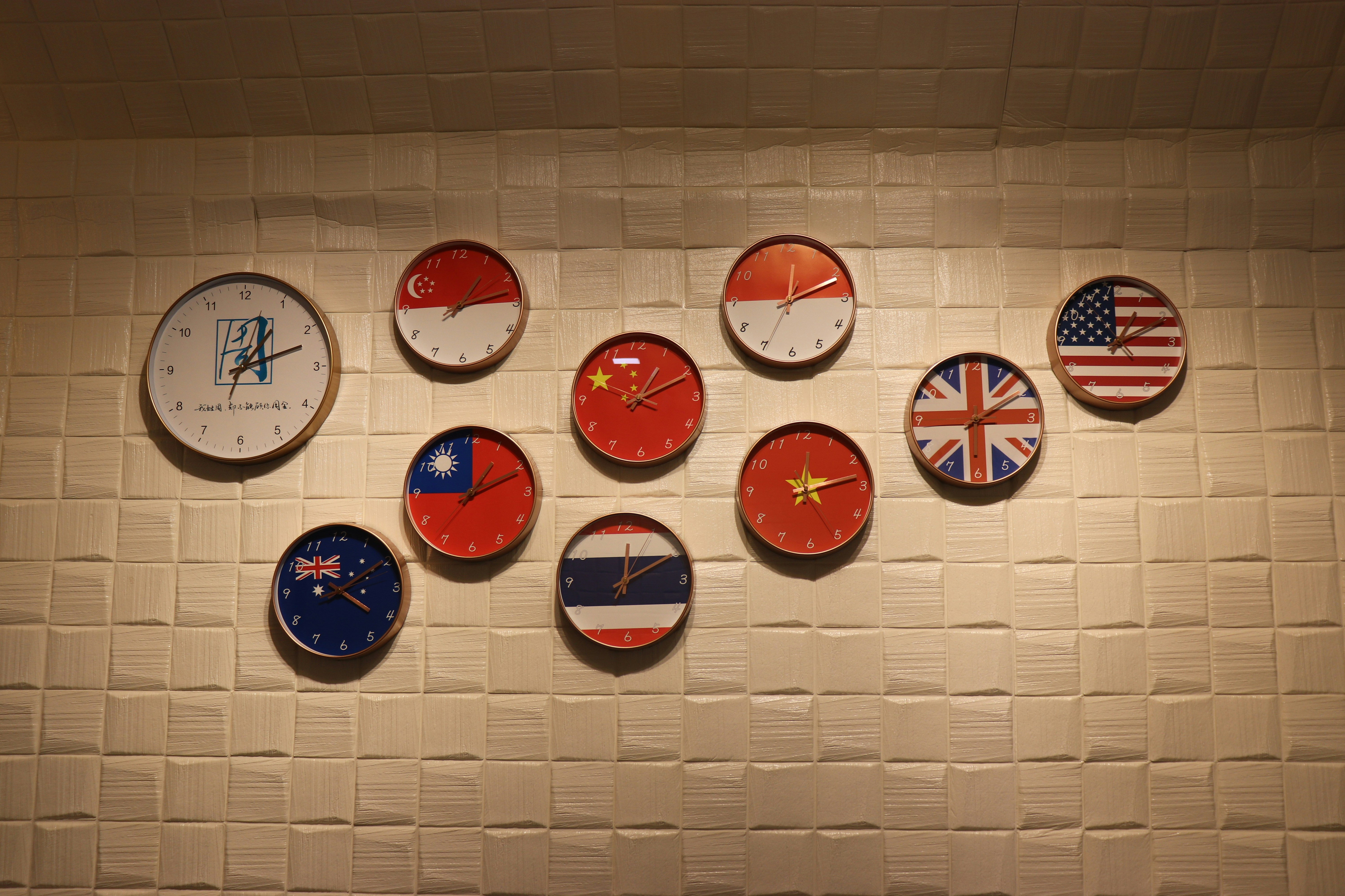Wall display of multiple clocks showing different time zones, each featuring the flag of a different country, symbolizing global connectivity and international coordination.