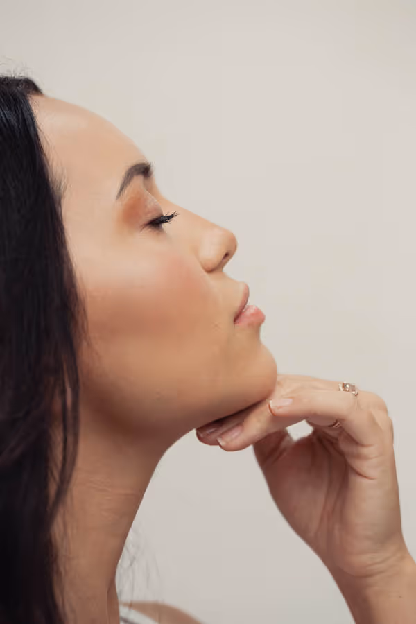 Close-up of a woman’s side profile with her eyes closed and a hand under her chin