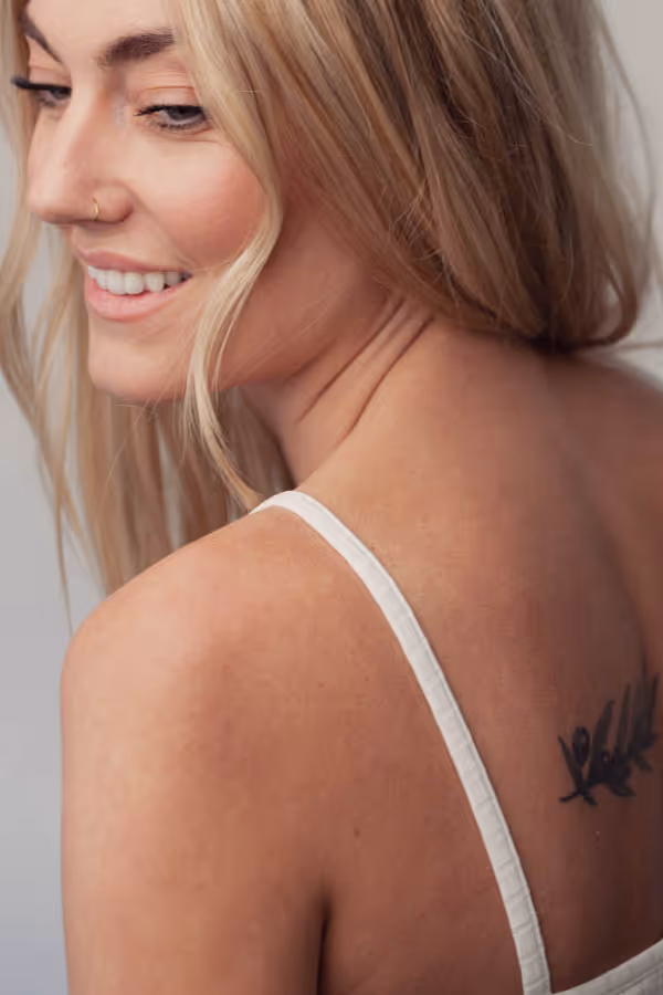 Woman looking over her shoulder with a visible tattoo in the center of her back