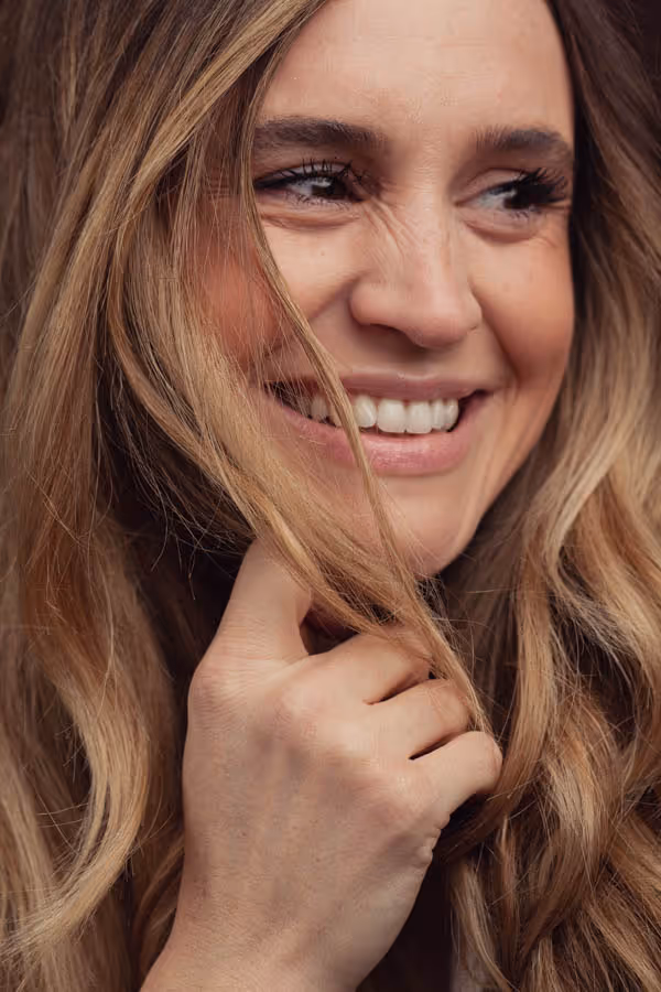 Close-up of the face of a smiling woman with her hand under her chin