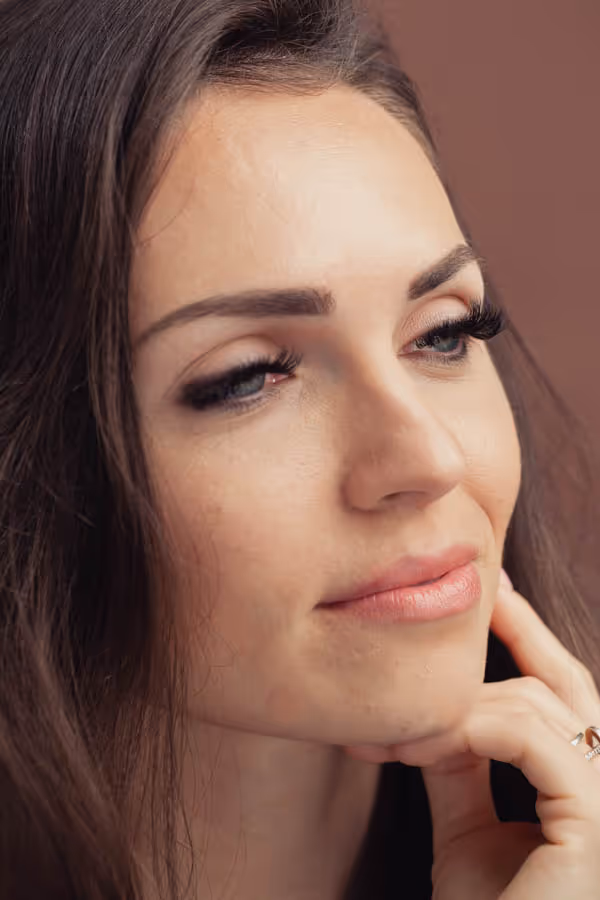 Headshot of a dark-haired woman with her hand at her jaw 