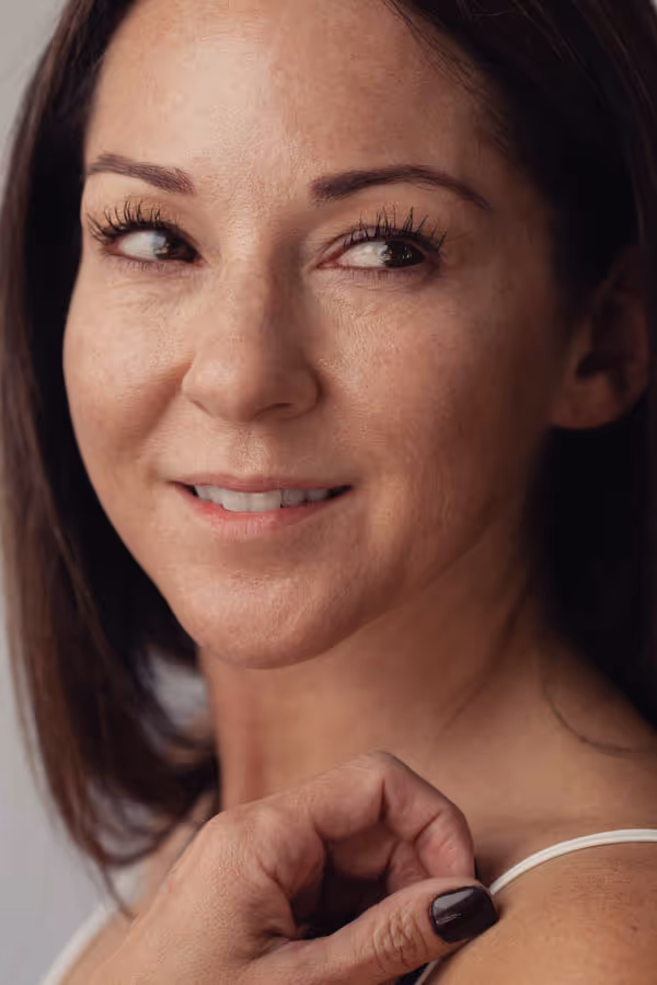 Headshot of a woman looking sideways with one hand on her shoulder