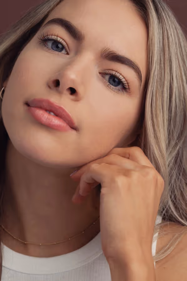 Headshot of a blond woman with one hand at her jaw