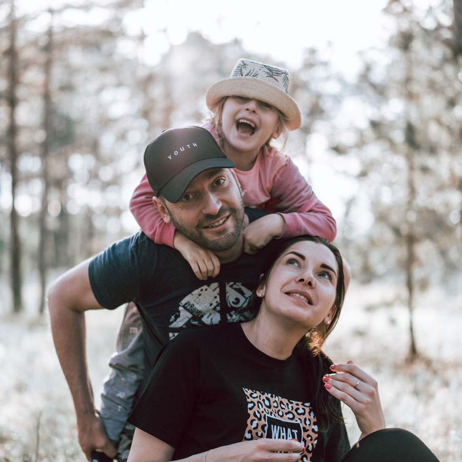 photo of happy family: a daughter laughing on dad's back and wife looking up at dad