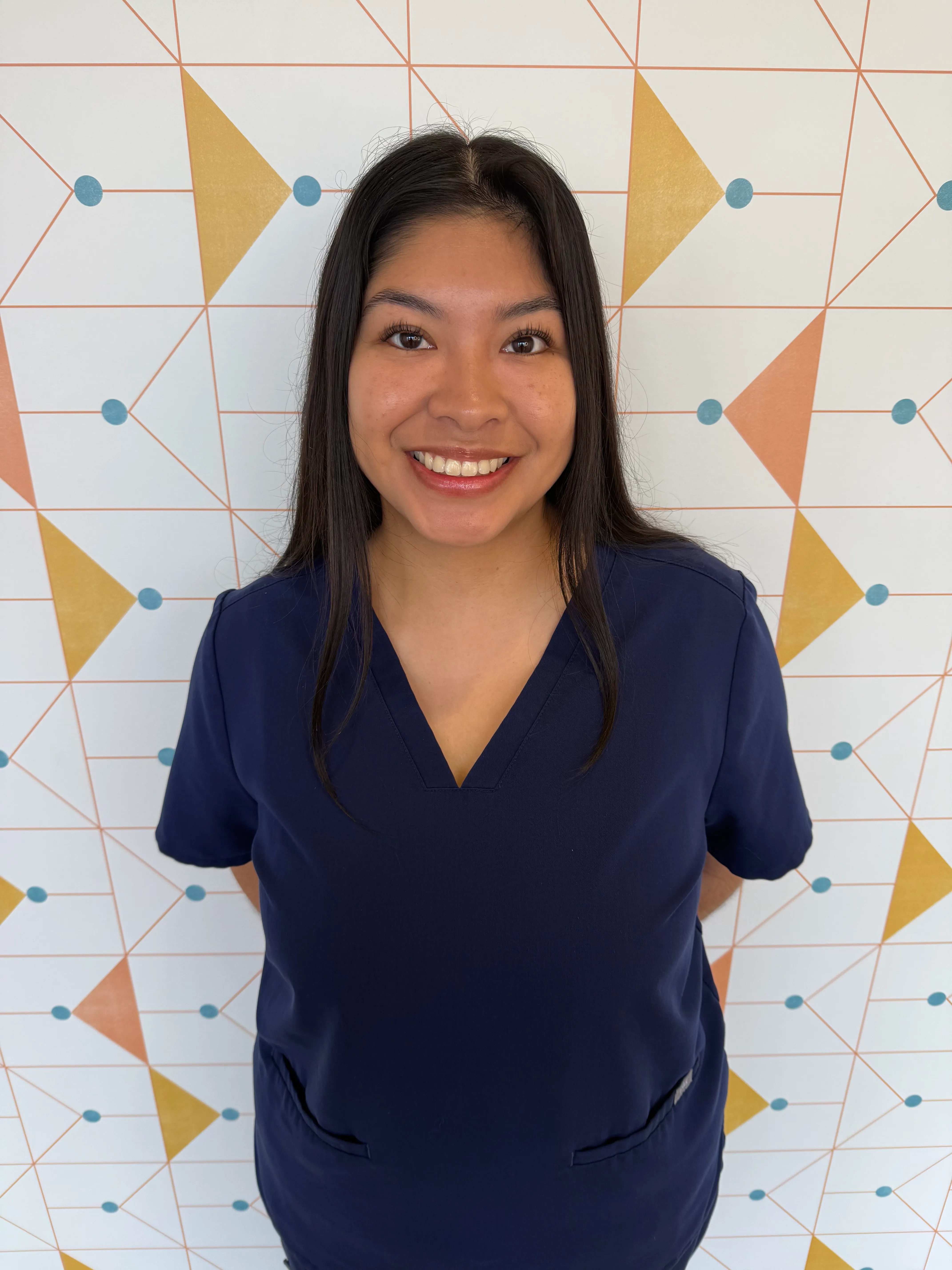 Gabriela, a dental assistant at Poppy Kids, smiling in her uniform.