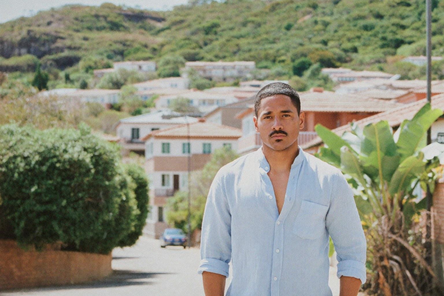 Man in a light blue linen shirt on a leafy hillside street in a Latin American city