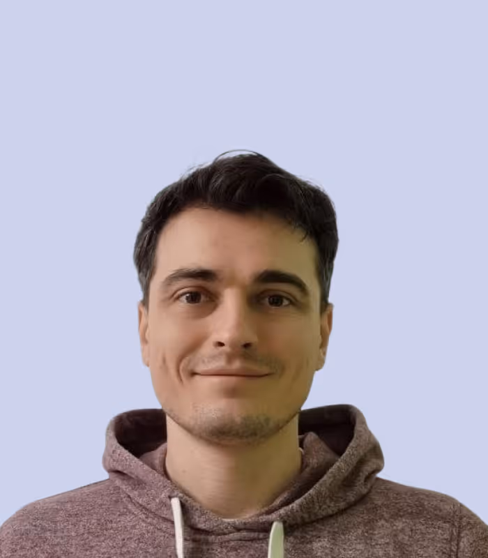 Junger Mann mit dunklen Haaren und Kapuzenpullover vor blauem Hintergrund.