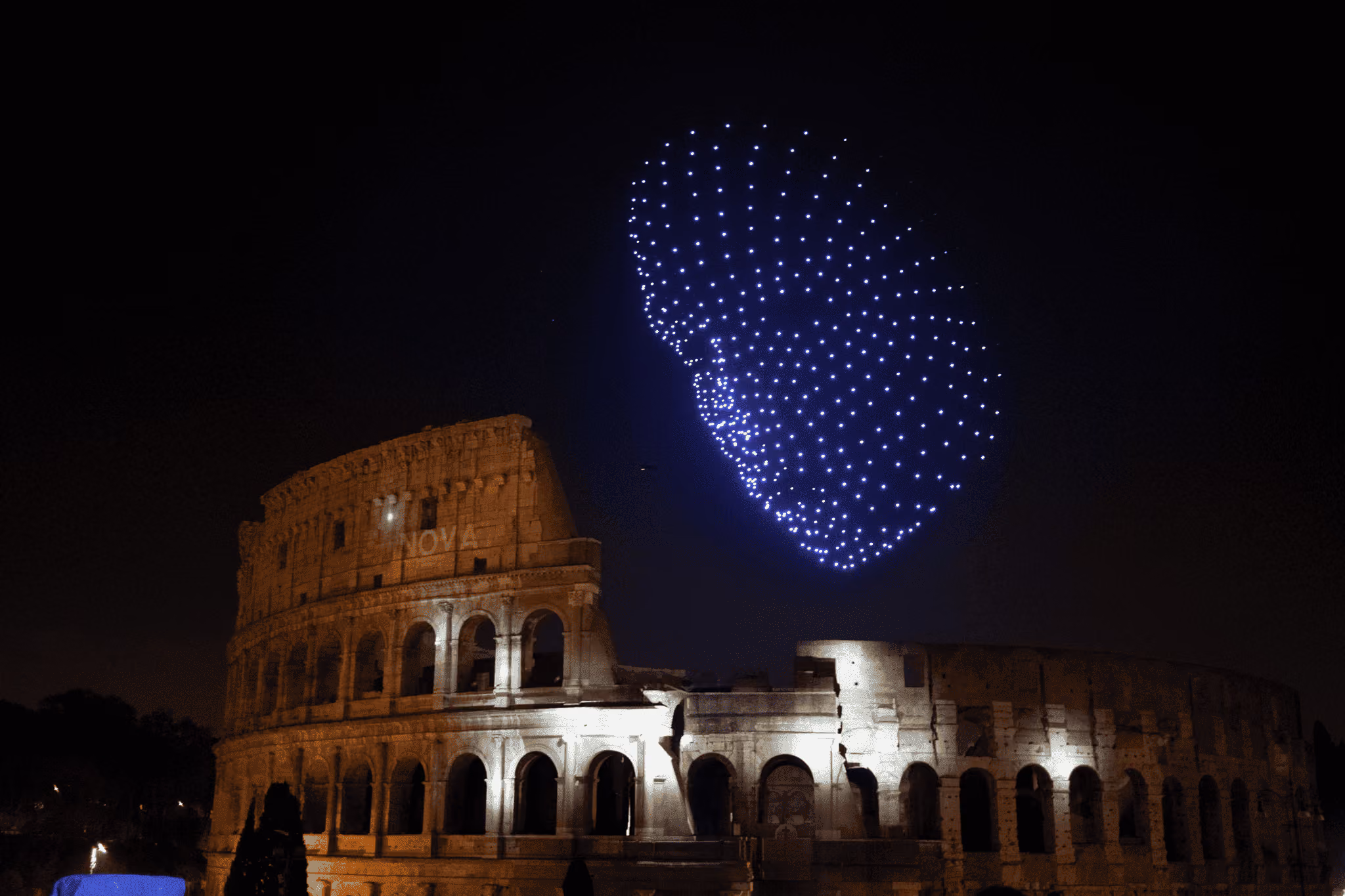 Dronisos drone light show forming a giant face above the Colosseum in Rome at night
