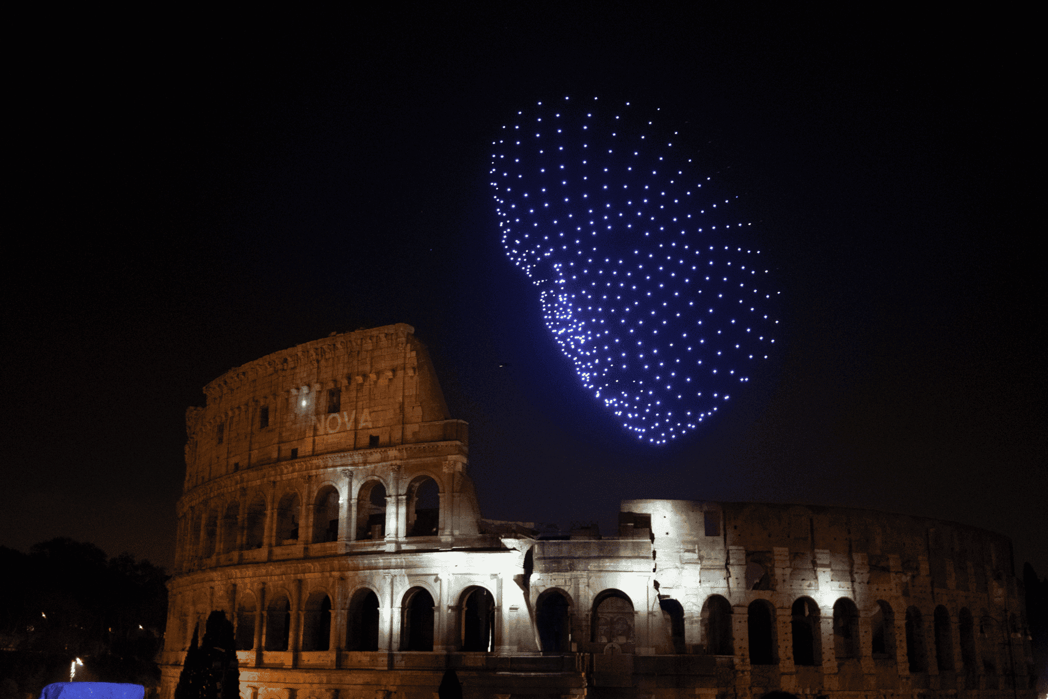 Dronisos drone light show forming a giant face above the Colosseum in Rome at night