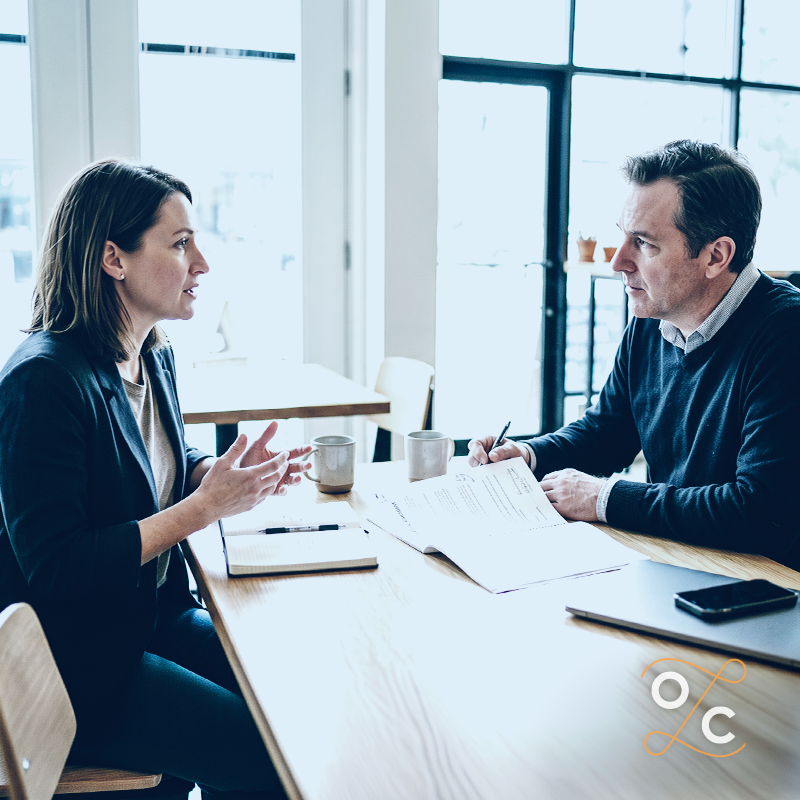 Two business professionals reviewing a contract across a table, illustrating how good faith and fair dealing can affect the exercise of contractual rights and business decisions.