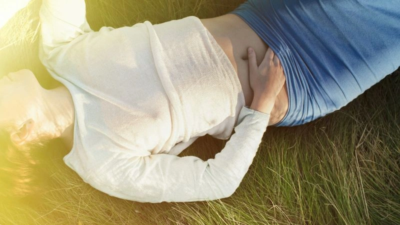 Person holding their stomach while experiencing digestive issues associated with SIBO vs IBS