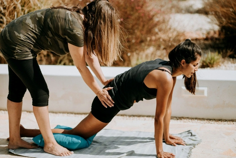 Physiotherapist assisting a woman with a stretching exercise outdoors, illustrating osteopathy vs physiotherapy approaches.