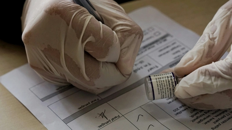 Close-up of gloved hands recording sample information during a laboratory toxicity test