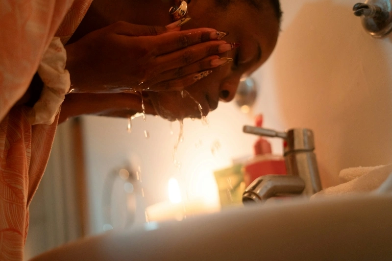 Woman washing her face with water to soothe skin discomfort and a prickling sensation