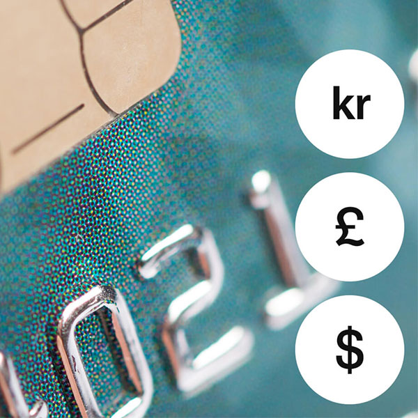 Lähikuva maksukortista, esillä valuuttasymbolit kruunu, punta ja dollari.