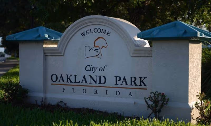 Welcome sign for the City of Oakland Park, Florida, set between two pillars with blue caps.
