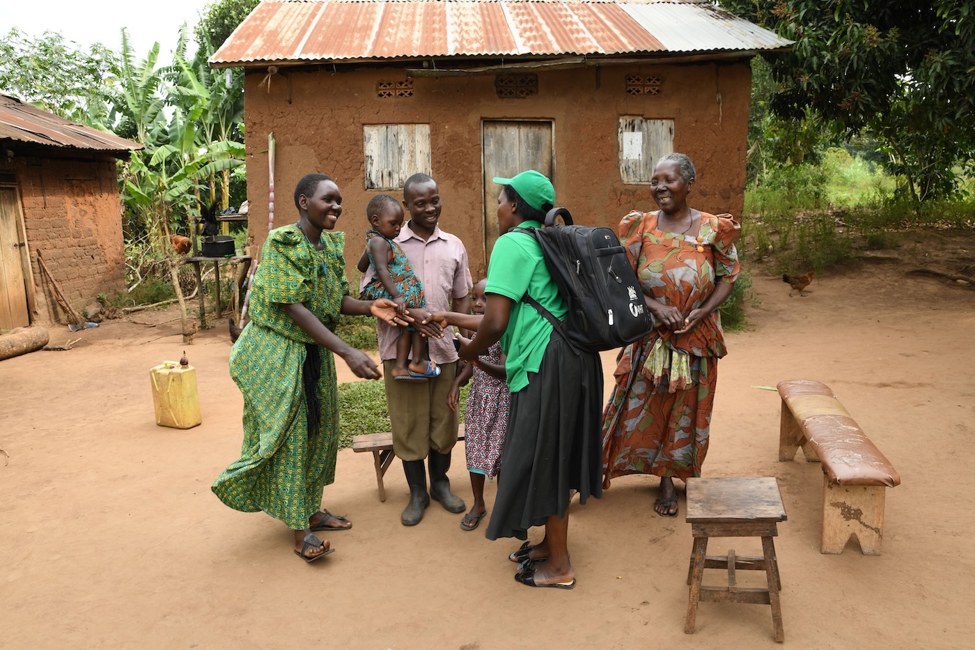 Woman with a backpack greeting a family in front of their house.
