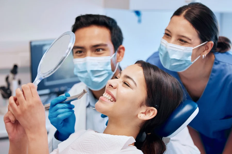 houska-dental-patient-smiling-with-dental-team-after-checkup